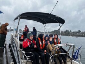 Community members in rain gear sitting on boat for a guided tour of West Bay