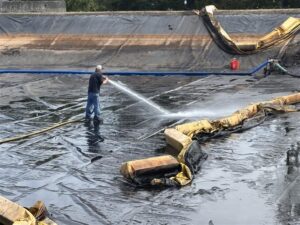 A staff worker at the Port of Olympia spraying hose to remove sediment from its stormwater treatment ponds.
